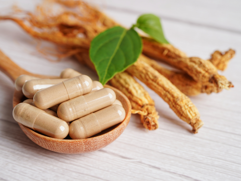 Erectimus Capsules next to some fresh herbs used in the formula